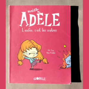 Couverture du tome 2 de Mortelle Adèle L’enfer, c’est les autres – Adèle donnant un coup de pied à un chat bleu, sur fond rouge